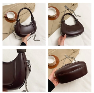 Detail view of dark brown crescent bag with silver chain strap and ball handle decor