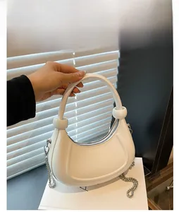 Detailed macro view of a white crescent hobo bag featuring silver chain and smooth handle