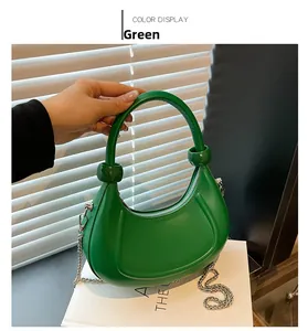Close-up of green leather hobo bag with round top handle and silver chain strap details