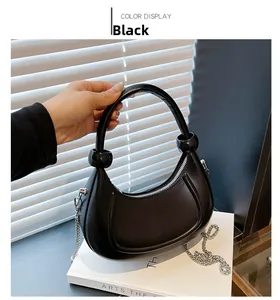Detail of black crescent hobo bag featuring matte finish and silver metal chain strap