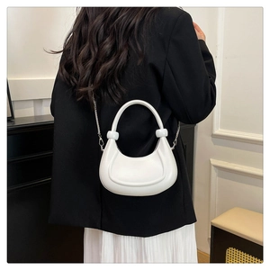 Detail view of a white crescent shoulder bag with silver chain strap and beaded handle