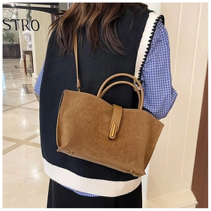 Macro detail of brown suede tote bag with golden metal clasp and smooth handle