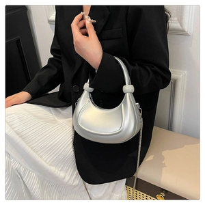 Detail of silver half-moon bag featuring metallic gloss texture and spherical handle decor