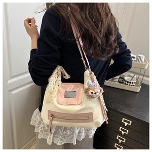 Detail of canvas tote bag featuring pink accents, lace bow, and plush bear charm