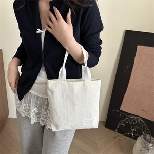 Off-white corduroy bucket bag with woven handles shown in a lifestyle setting