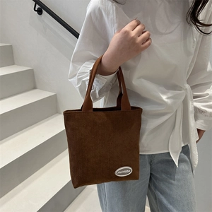 Brown corduroy bucket tote bag with top handle and logo patch for casual styling