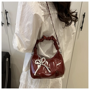 Détail du sac nuage rouge en similicuir avec nœud en perles et poignée à volants
