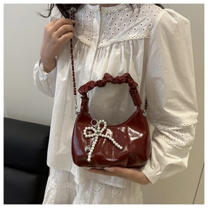 Détail du sac nuage en cuir verni bordeaux avec nœud perlé et poignée plissée