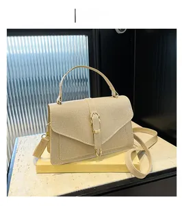 Detail of khaki crossbody bag with gold curved metal clasp on stone surface