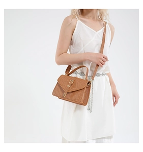 Détail de la texture tressée et boucle dorée en fer à cheval sur le sac marron