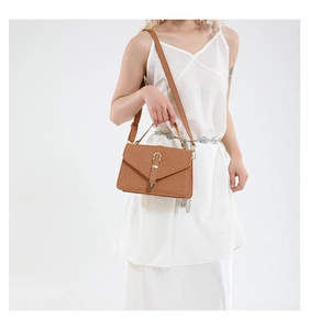 Close-up of caramel woven texture envelope handbag with metallic clasp and leather strap