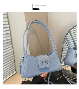 Close-up of sky blue baguette bag featuring a textured fabric and silver metal bow