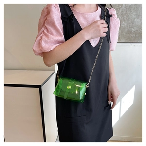 Detail van de groene transparante crossbodytas met gouden ketting op een model