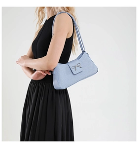 Détail d'un sac baguette bleu clair avec boucle nœud argenté porté par un mannequin