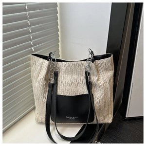 Dettaglio borsa tote in paglia intrecciata con tasca in pelle nera e tracolla a catena