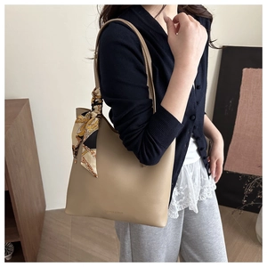 Détail du sac cabas kaki avec nœud en foulard de soie et texte sur la surface en cuir