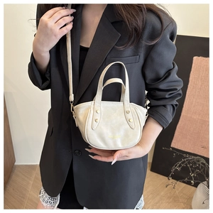 Detail of cream white bucket bag with gold rivets and leather texture worn on model
