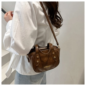 Detail of vintage brown leather bucket bag with top handles and metallic rivet accents