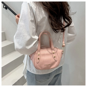 Detail of pink PU leather bucket bag with gold rivets on a minimalist stair background