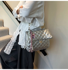 Detail of silver quilted tote bag with golden twist lock and decorative charms