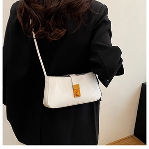 Chic beige underarm bag with gold clasp shown on a shoulder over a black blazer