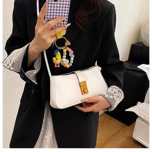 Close-up of a white leather underarm bag featuring a gold metal twist lock buckle