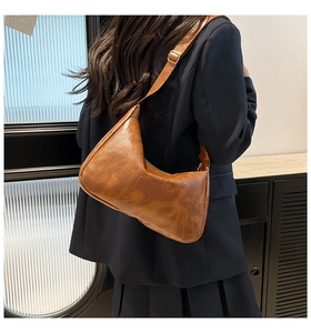 Detailed close-up of brown PU leather shoulder bag with FASHION engraving and metal buckle