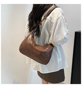 Model wearing a retro brown faux leather hobo shoulder bag with adjustable strap