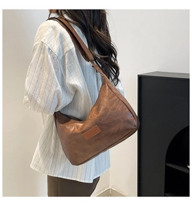 Detail view of the brown retro pillow bag showing worn leather texture and wide strap