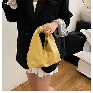 Détail d'un sac seau plissé jaune vif avec texture en cuir souple et poignée élégante