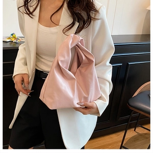 Gros plan du sac nuage plissé rose clair avec poignée nouée porté par un mannequin