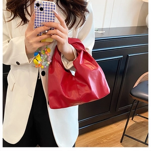 Détail du sac hobo rouge avec poignée nouée tendance et texture plissée mate