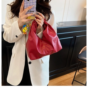 Détail du sac à main rouge vif en cuir plissé avec un design moderne en nuage