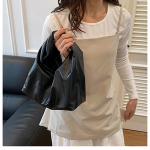 Gros plan d'un sac cabas noir minimaliste porté par un mannequin dans un intérieur