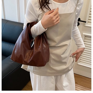 Gros plan sur un sac hobo en cuir souple marron foncé avec plis naturels et reflets