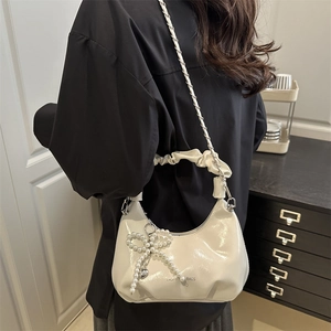 Sac nuage blanc en cuir verni avec nœud en perles et bandoulière sur mannequin