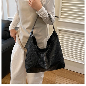 Detail of black woven texture on a large hobo bag with a fashion leather tag hanging