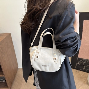 Minimalist beige leather handbag with vintage studs shown on a professional model