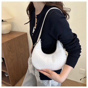Close-up of white woven crescent shoulder bag showing textured faux leather and sleek zipper