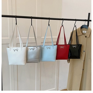 Détail de cinq sacs cabas colorés avec des nœuds métalliques sur un support de vente