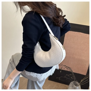 Detail of white woven crescent shoulder bag with silver zipper and fine texture