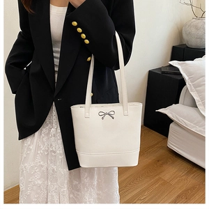 Détail du sac cabas blanc avec nœud en métal argenté et fine bandoulière sur modèle