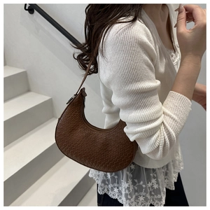 Close-up of brown crescent hobo bag with woven texture on model for style reference