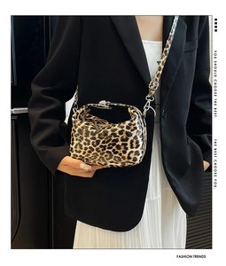 Detail of glossy leopard print crossbody bag with silver metal lock and top handle