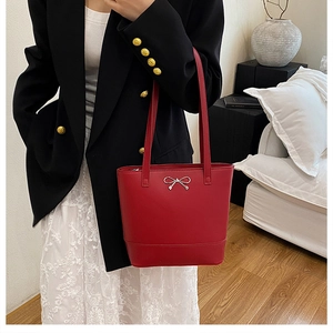 Détail du cabas rouge avec un nœud argenté et une texture en cuir synthétique chic