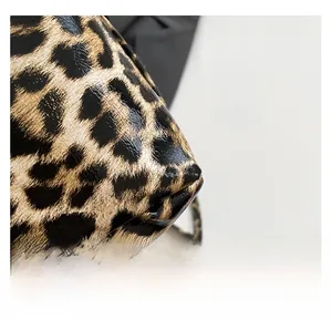 Macro view of glossy leopard print faux leather texture with fine metal chain strap