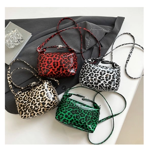 Flat lay of small leopard print underarm bags in red, black, brown, and green