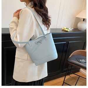 Détail du sac seau bleu clair avec un nœud argenté sur cuir mat lisse et élégant