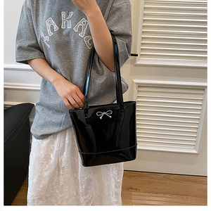 Détail du sac cabas en cuir verni noir avec nœud en métal argenté et doubles bretelles
