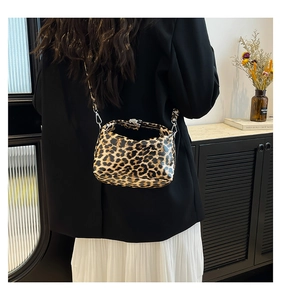 Detail of leopard print glossy crossbody bag with silver hardware on a fashion model